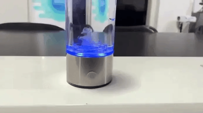 Portable Hydrogen Water Generator bottle with blue LED base creating hydrogen-infused water on a modern office desk