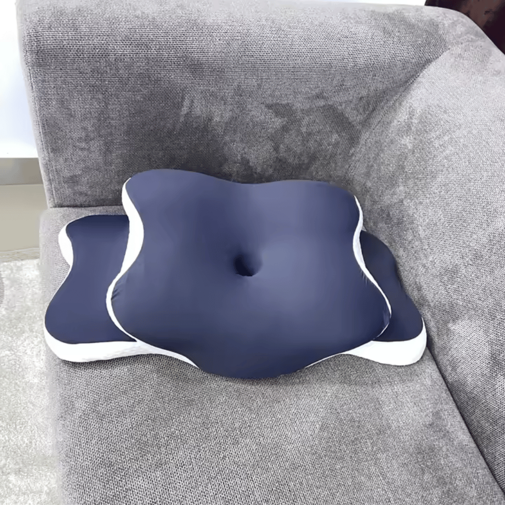Navy orthopedic memory pillow placed on a grey sofa.