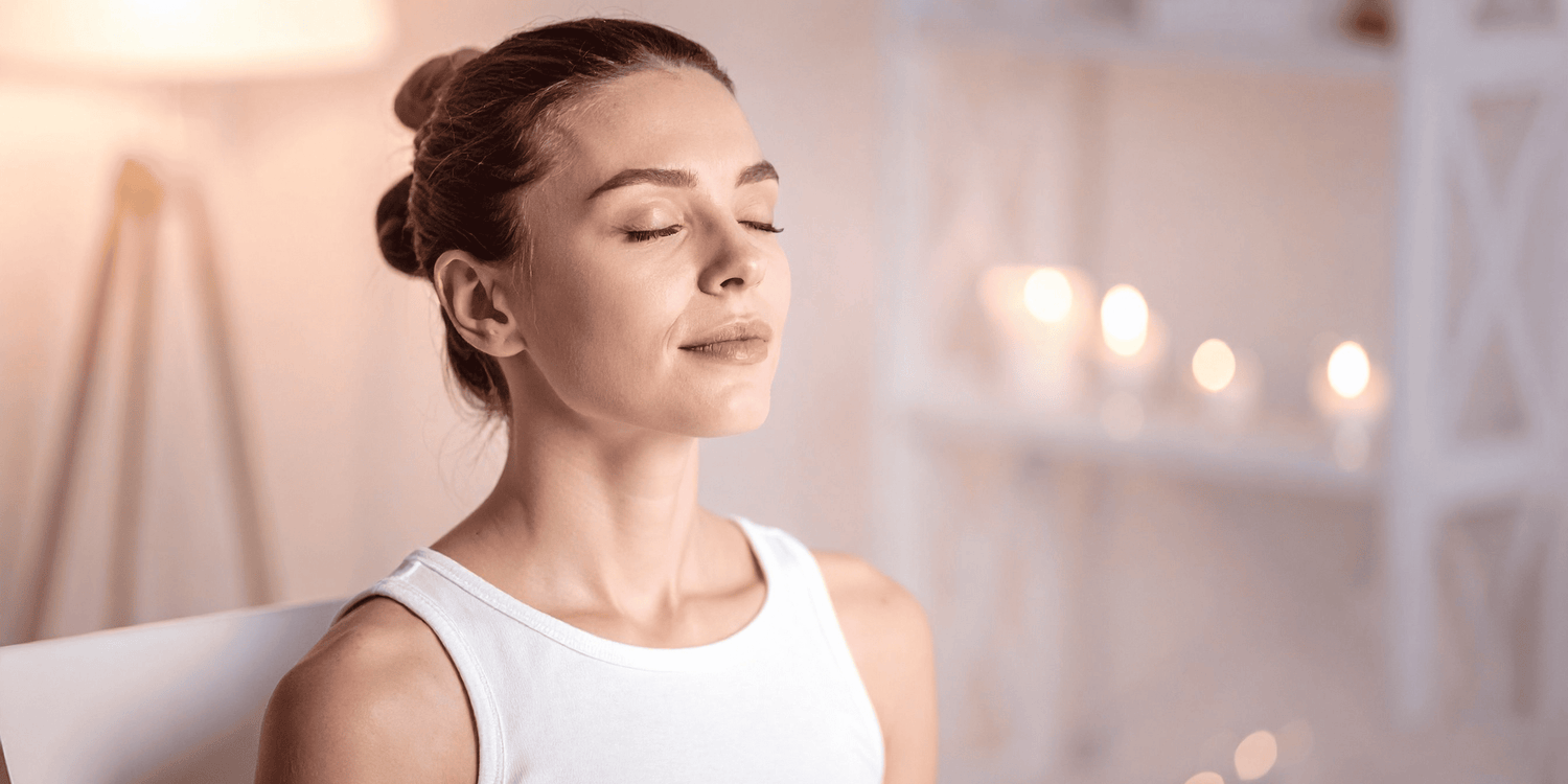 Woman with closed eyes relaxing in a calm, softly lit room – representing DDrelax self-care and serenity.