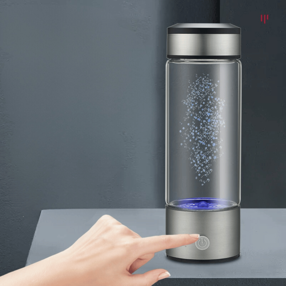 Glass water bottle with a silver base and black lid, showing bubbles inside, on a dark surface.